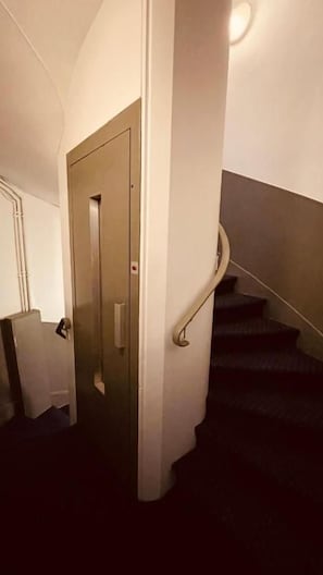 A staircase with a handrail, a door, and a light fixture. - Jeff Hotel Paris (Paris)