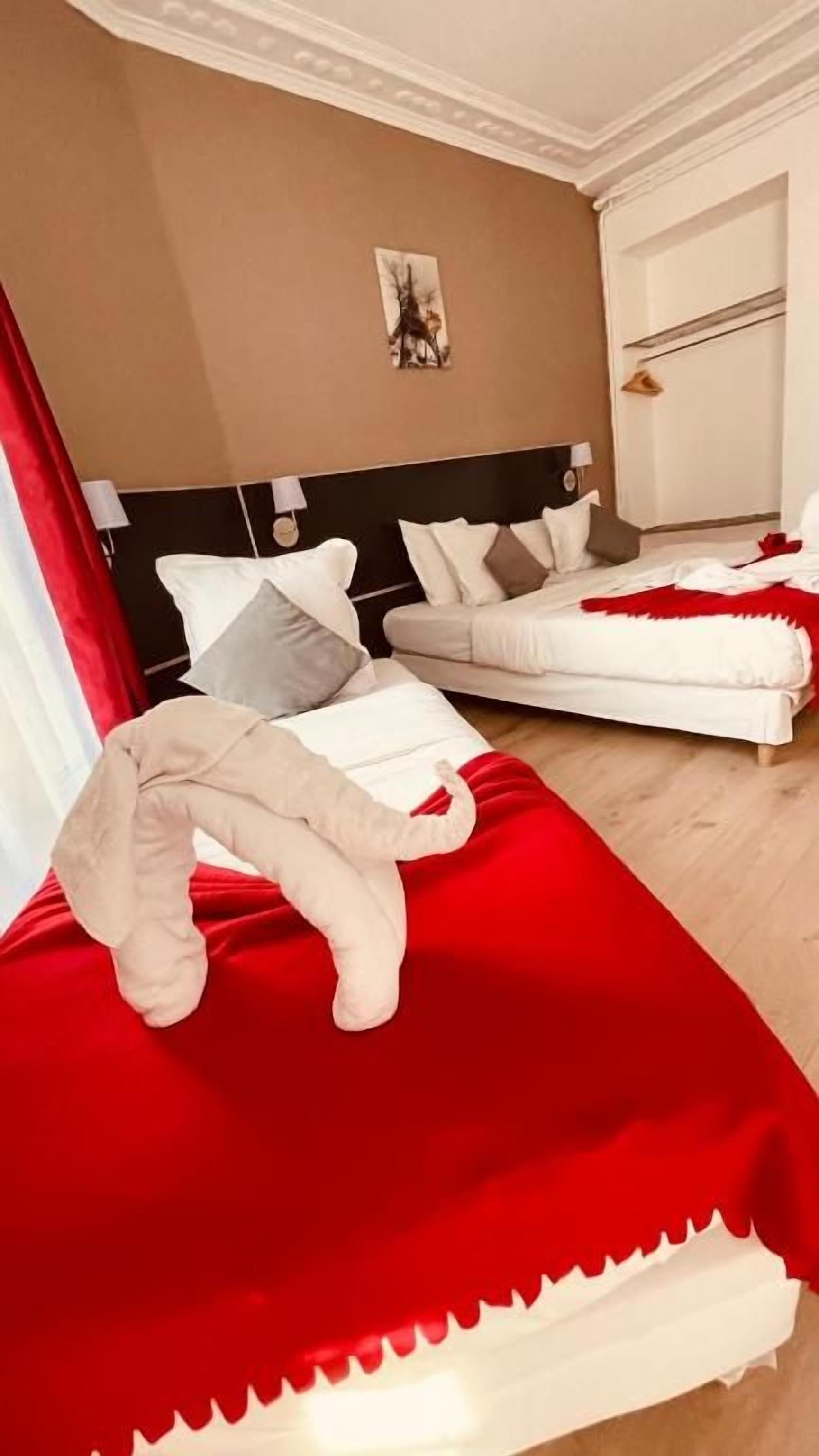 A hotel room with two beds, a red and white bedspread, and a painting on the wall.