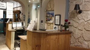 A reception desk with a wooden counter, a computer, and a framed certificate on the wall.