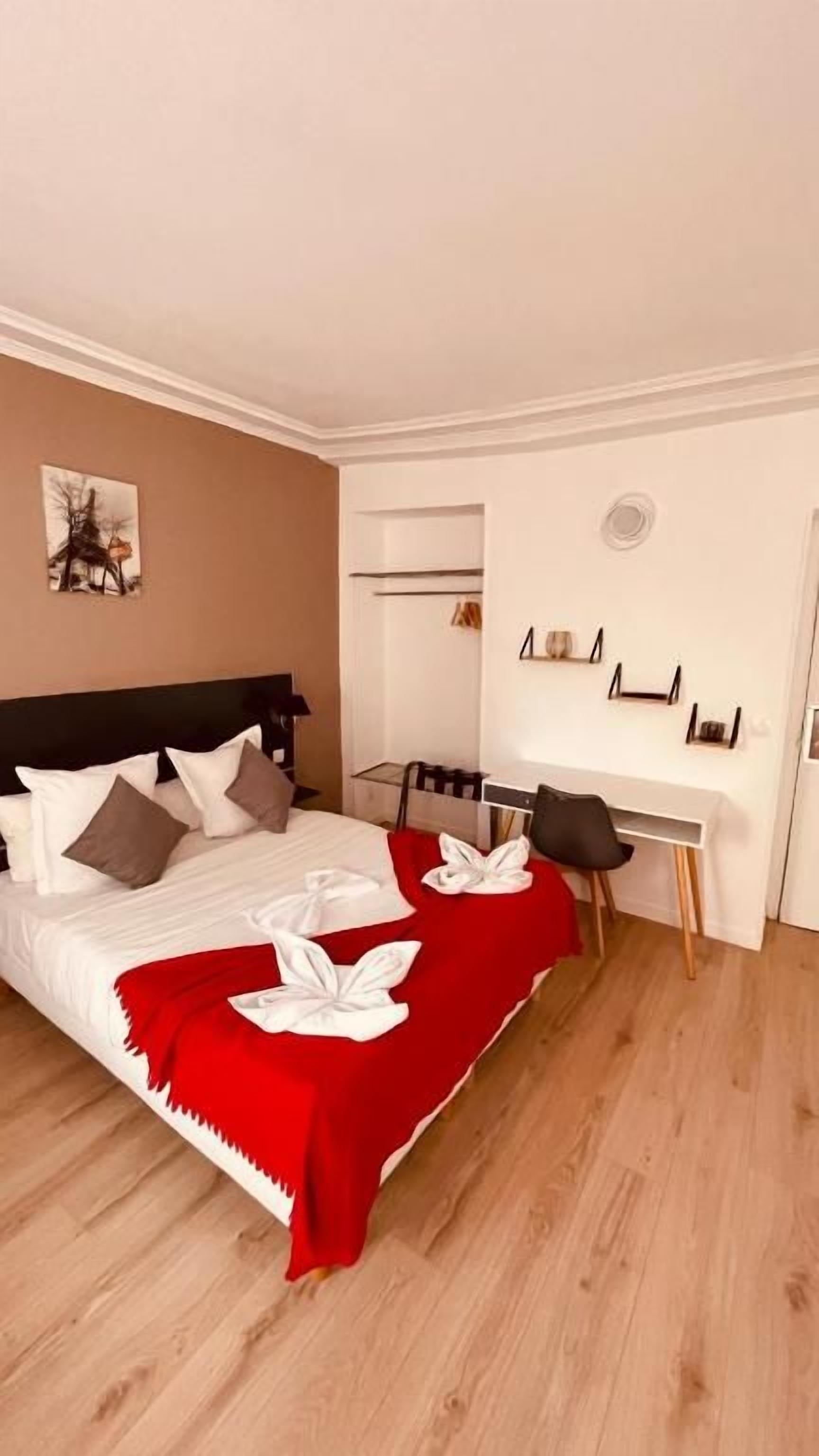 Quarto de hotel com cama, escrivaninha e cadeira.