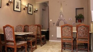 A dining area with ornate wooden chairs and tables, a wall mural of the Eiffel Tower, and framed pictures on the wall.