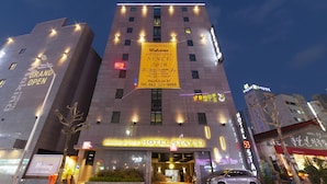 Un hotel con un gran letrero amarillo, varias ventanas y un estacionamiento.