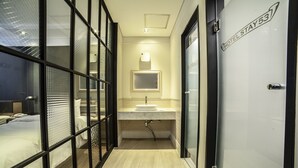 Una habitación de hotel con una cama, un baño con lavamanos y una puerta con la leyenda 'HOTEL STAY 53'.