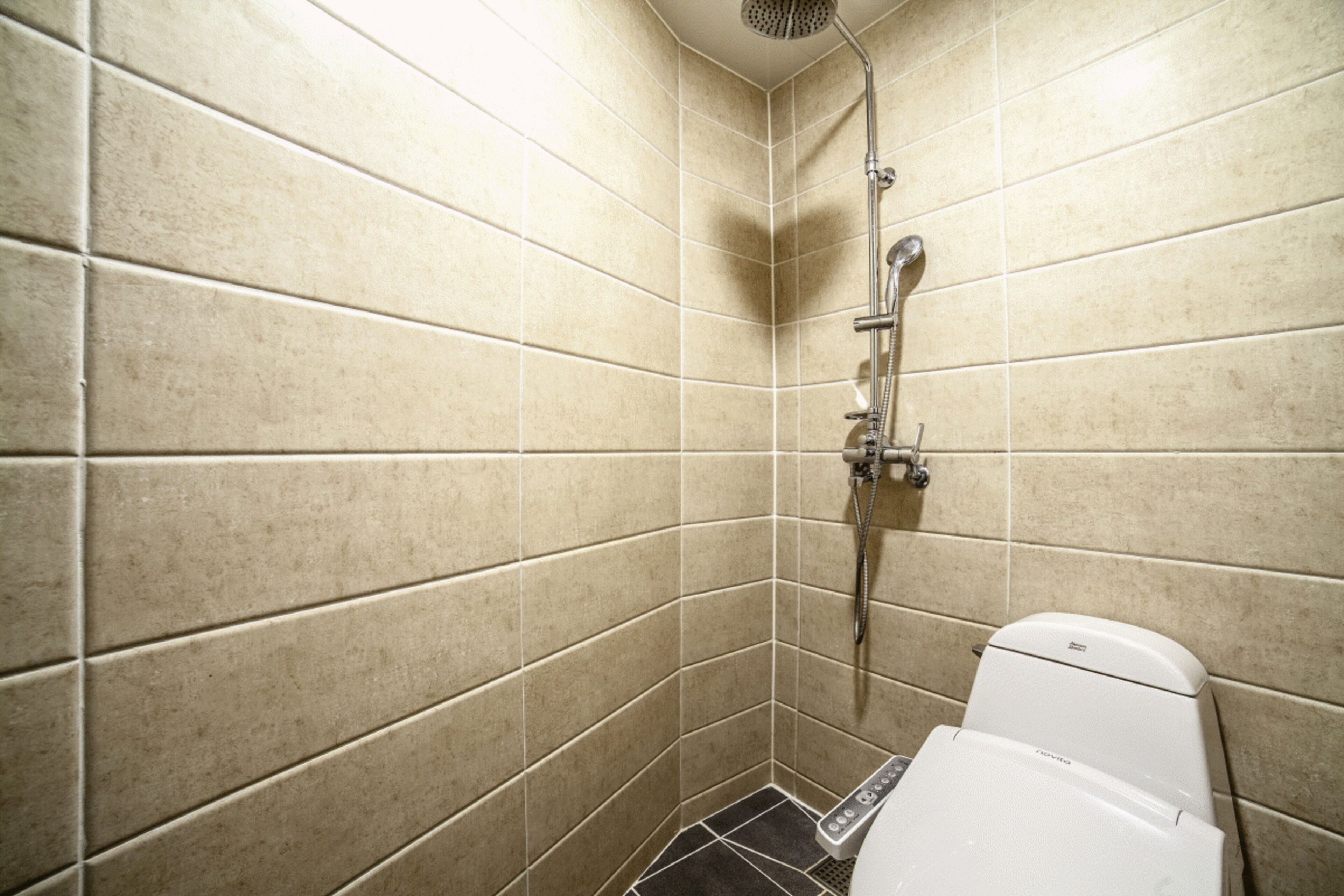 A small, tiled shower stall with a white toilet.