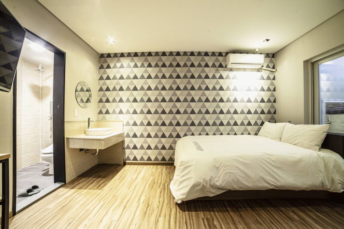 A hotel room with a bed, a sink, and a shower.