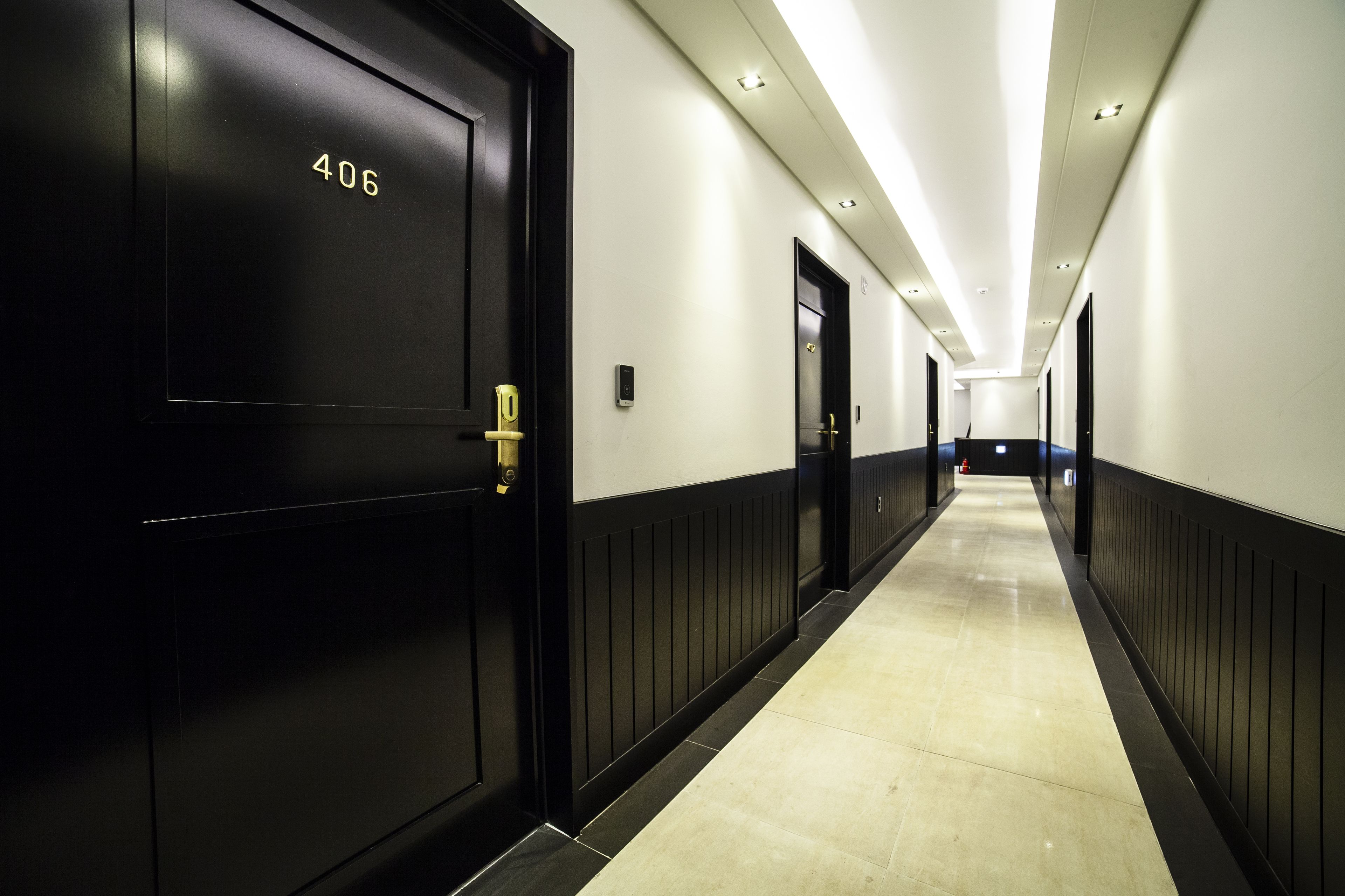 A long, narrow hallway with black doors, each marked with a number.