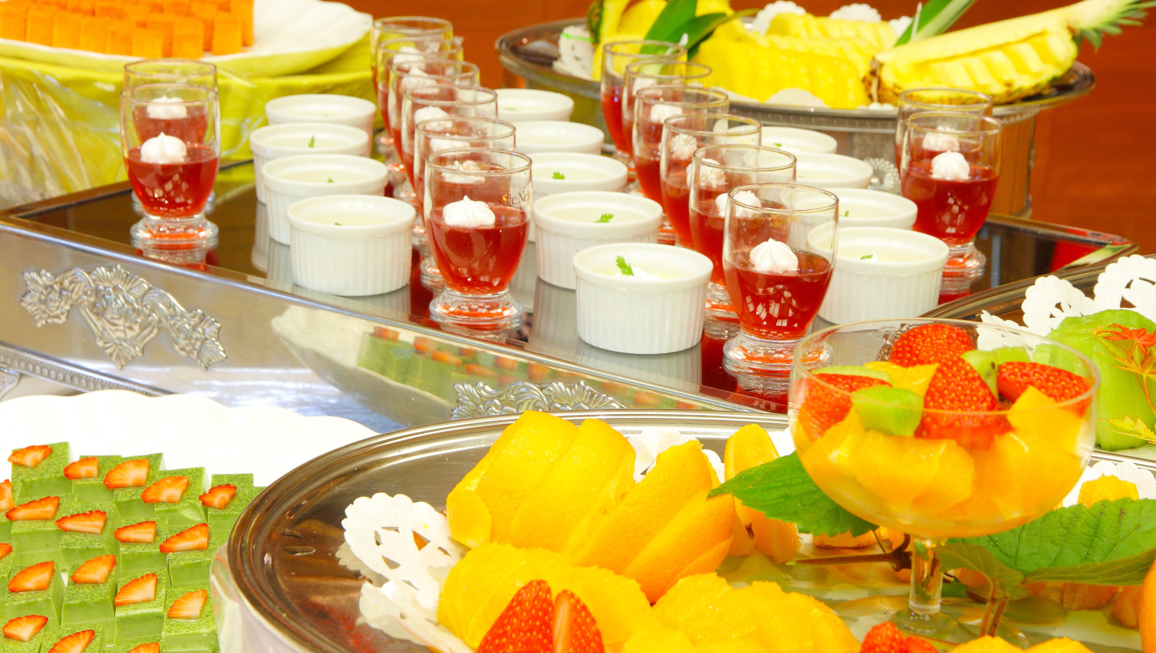 A buffet with various dishes including fruit, desserts, and beverages.