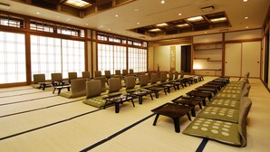 Ein traditioneller japanischer Raum mit Tatami-Matten, niedrigen Tischen und in Reihen angeordneten Stühlen.