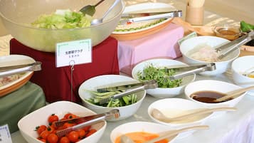 A buffet table with various dishes, including salads, vegetables, and sauces, with serving utensils.