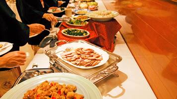 Una mesa de buffet con diversos platos, incluyendo una bandeja grande de carne en rodajas y un tazón de verduras mixtas.