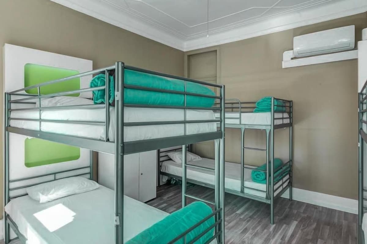 A bunk bed room with a small cabinet, a green pillow, and a white pillow.