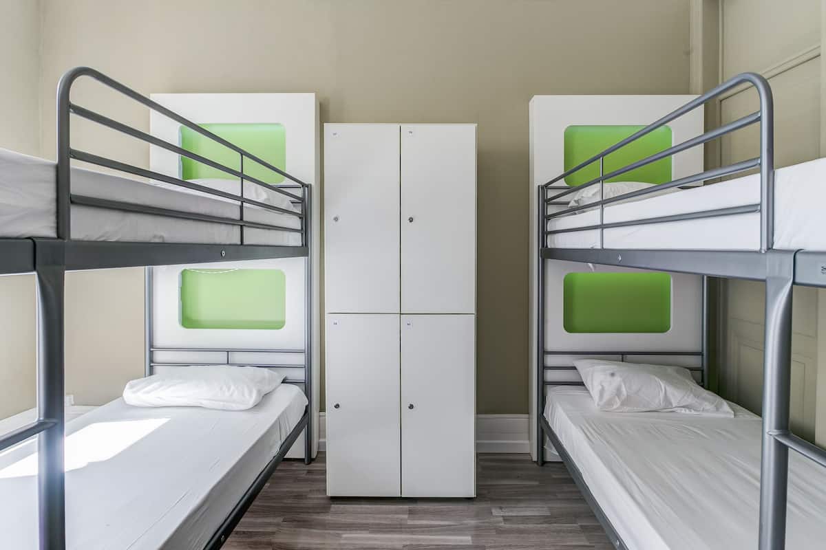 Ein Schlafsaalzimmer mit Etagenbetten, einem Kleiderschrank und einem Fenster.