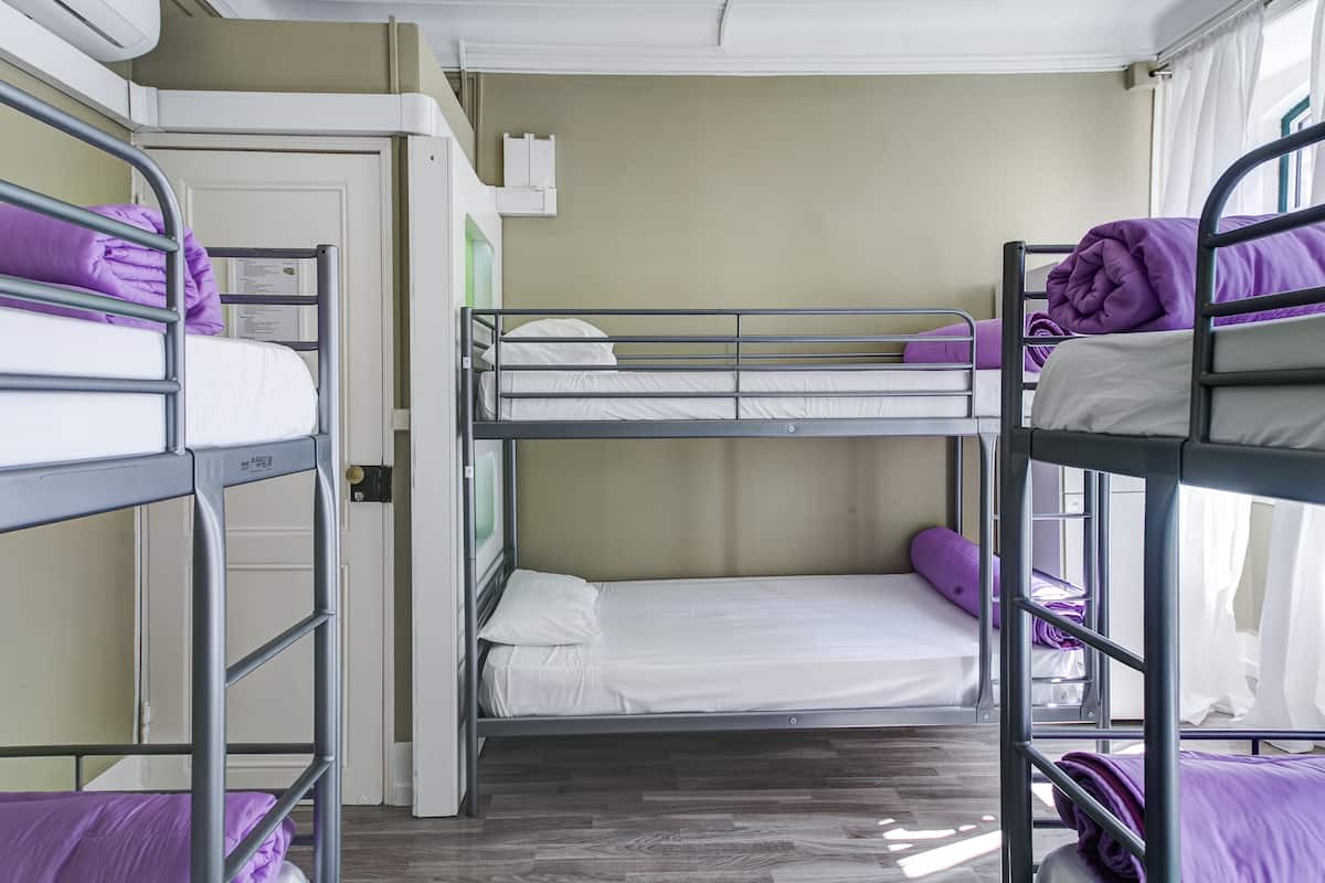 Ein Schlafzimmer mit Etagenbetten und drei Betten, jedes mit einer violetten Decke.