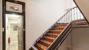 A staircase with wooden steps and metal railings, leading to a door with a sign above it. - Hostel Seven Hills (Lisbon)