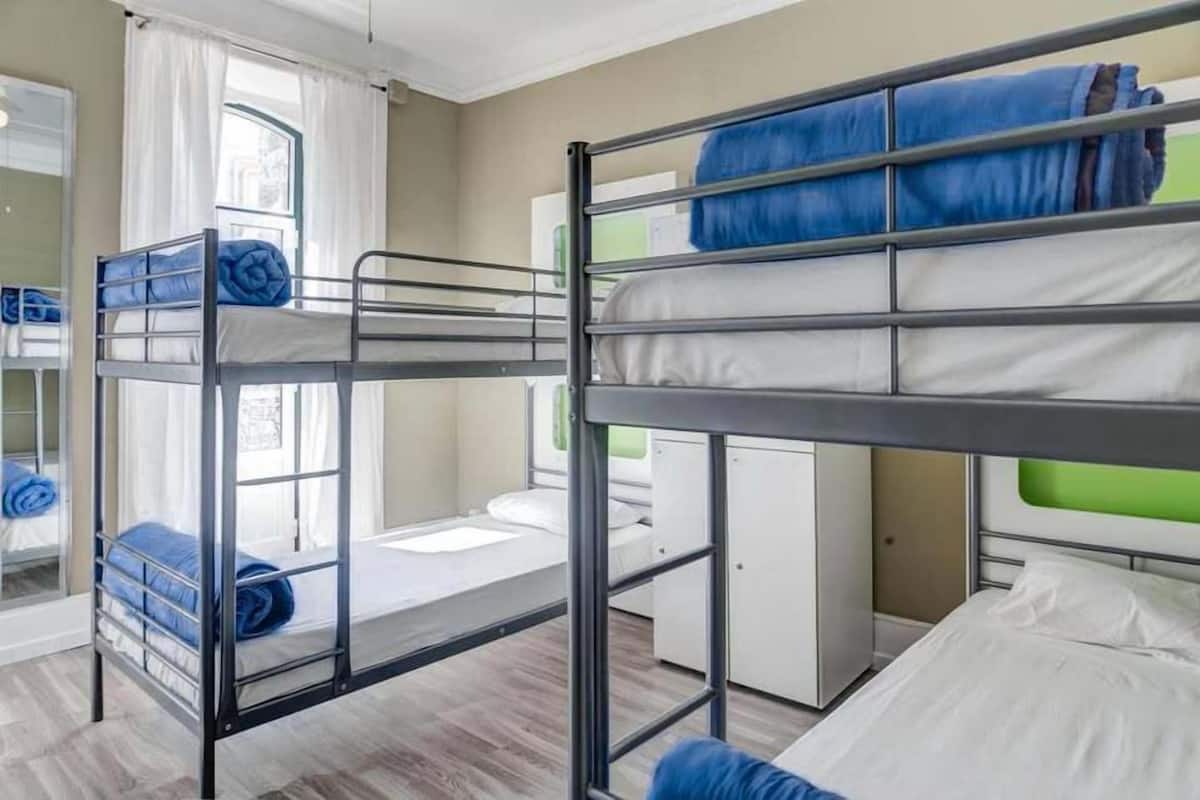 Ein Schlafzimmer mit Etagenbetten, einem Fenster, einem Schreibtisch und einem Kleiderschrank.