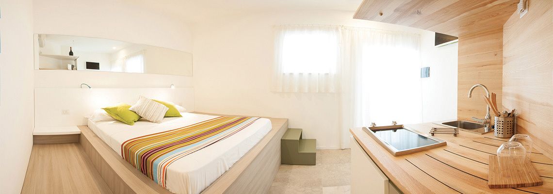 A modern bedroom with a bed, a wooden desk, and a bathroom area.