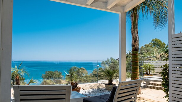 A covered outdoor seating area with a view of the sea. - A Tonnara (Cefalù)