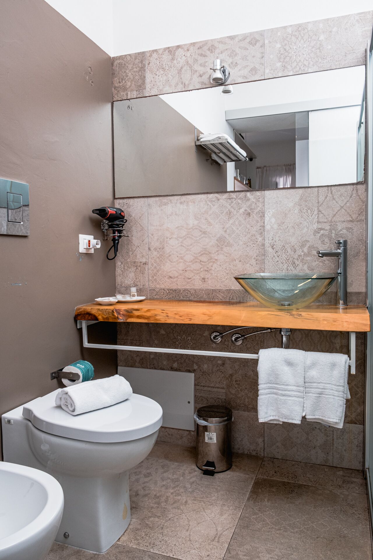 Un baño moderno con lavamanos de vidrio, un inodoro y un bidé.