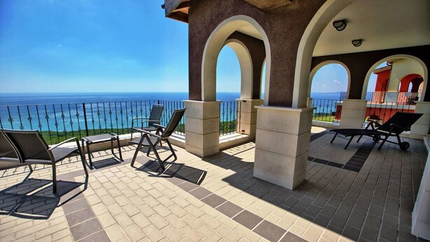 A terrace with outdoor seating, a view of the ocean, and a clear sky. - Lighthouse Apartments & Villas (Balchik)