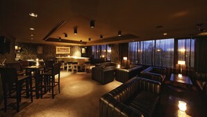 A dimly lit lounge area with leather seating, a bar, and a view of the outdoors through large windows. - Lighthouse Apartments & Villas (Balchik)