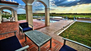 An outdoor patio with a pool, seating, and a view of a golf course. - Lighthouse Apartments & Villas (Balchik)