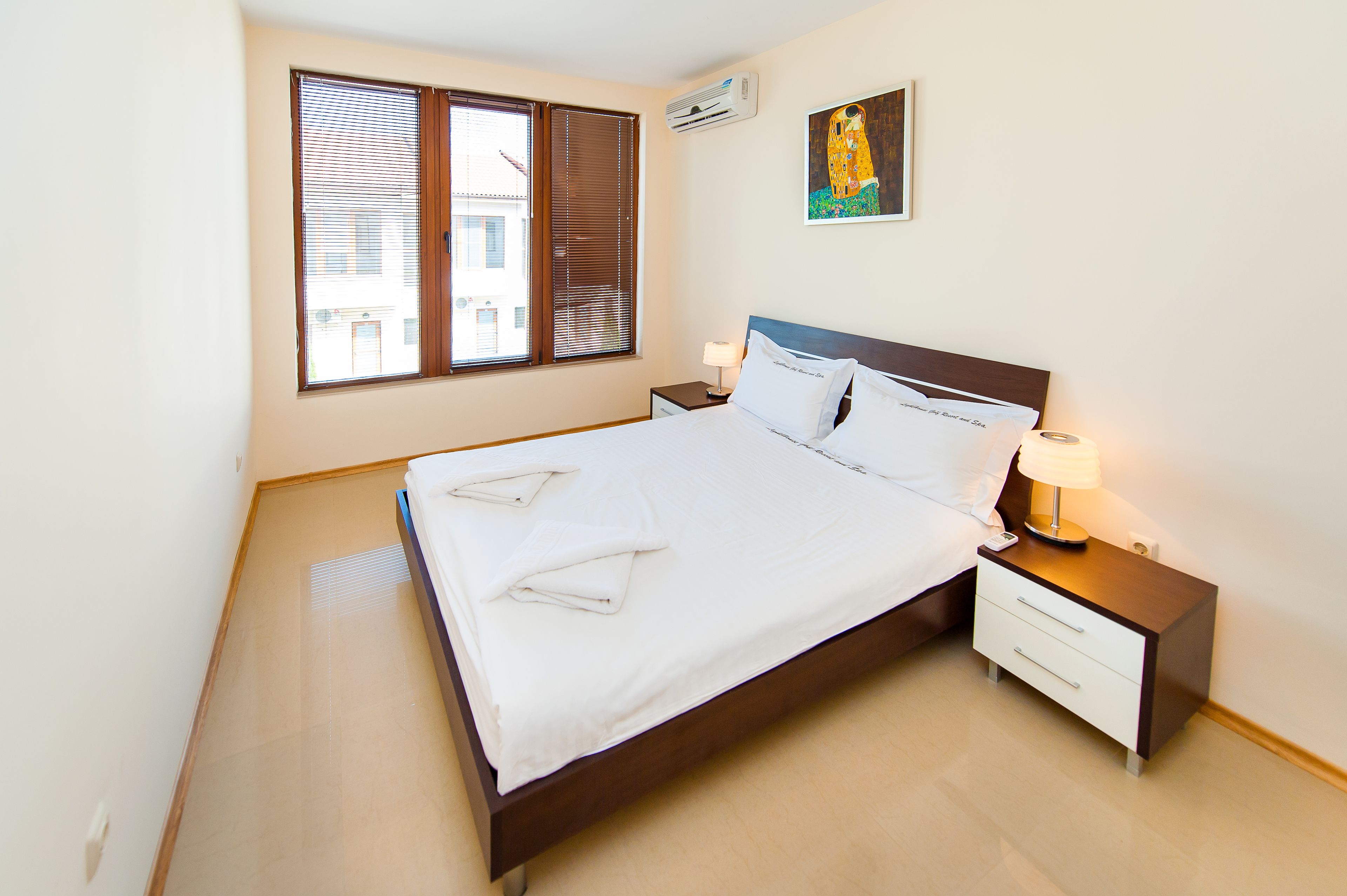 A neatly made bed with white linens, a wooden headboard, and a bedside table with a lamp.