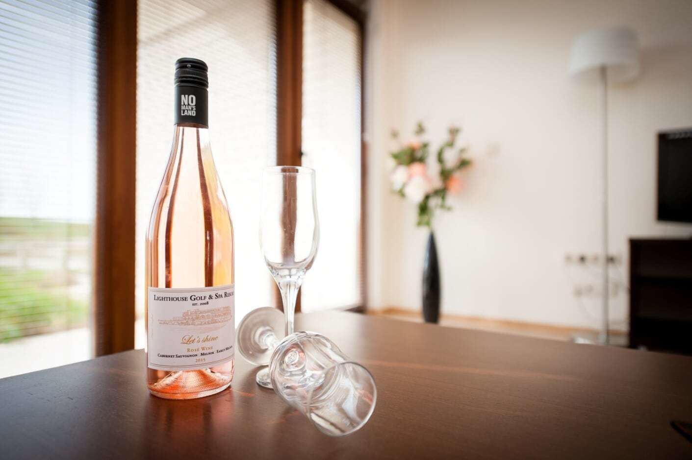 Eine Flasche Roséwein und ein Weinglas auf einem Holztisch.
