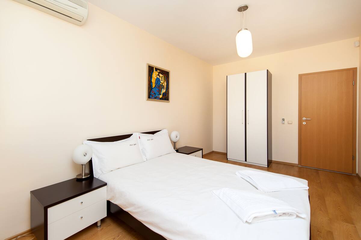 Ein Schlafzimmer mit einem Bett, Nachttischen, einem Kleiderschrank und einem Bild an der Wand.