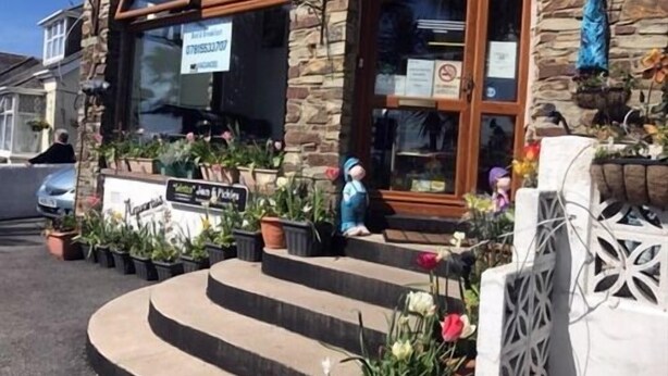 A storefront with a stone facade, a wooden door, and steps leading up to the entrance. - Aquarius B&B (Newquay)