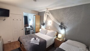 A hotel room with a bed, bedside tables, a TV, a mosquito net, and a view of the dining area. - Aquarius B&B (Newquay)