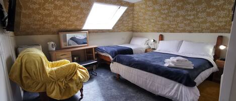 Een slaapkamer met twee bedden, een bureau, een stoel, een spiegel en een dakraam.
