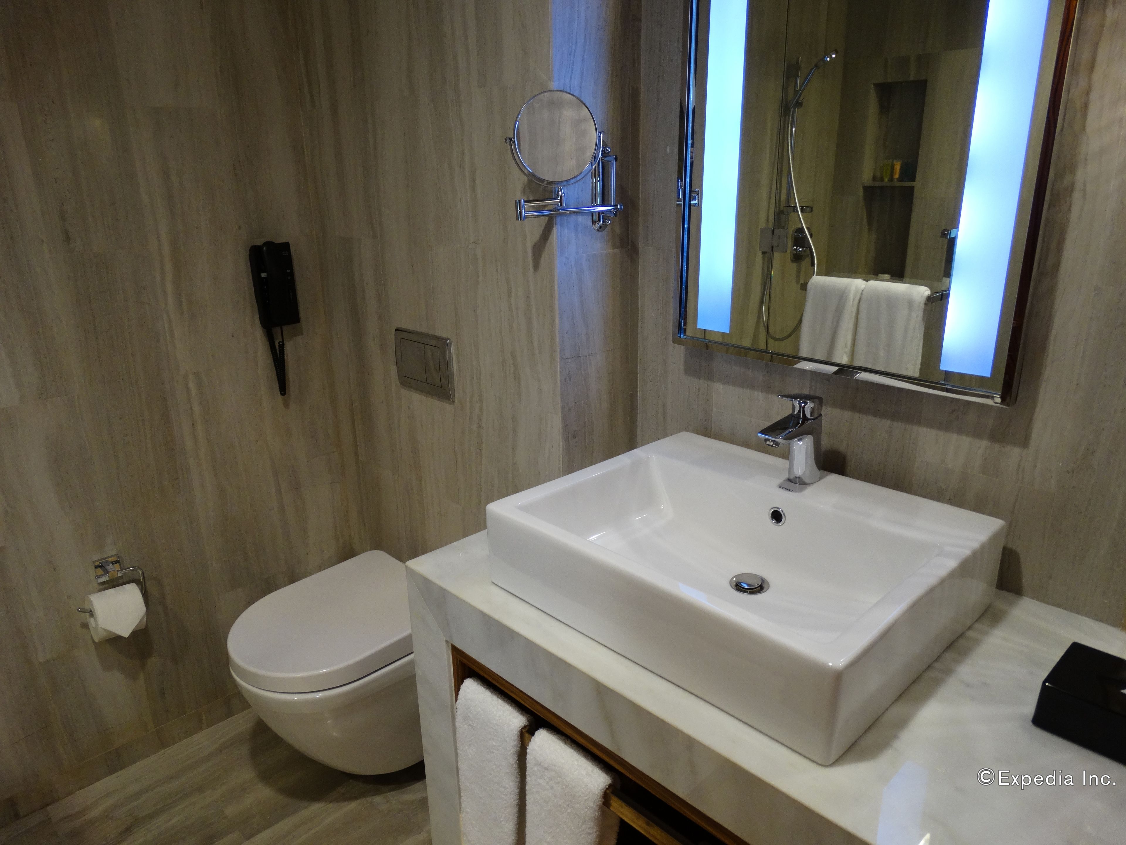 A modern bathroom with a white sink, toilet, and a large mirror.