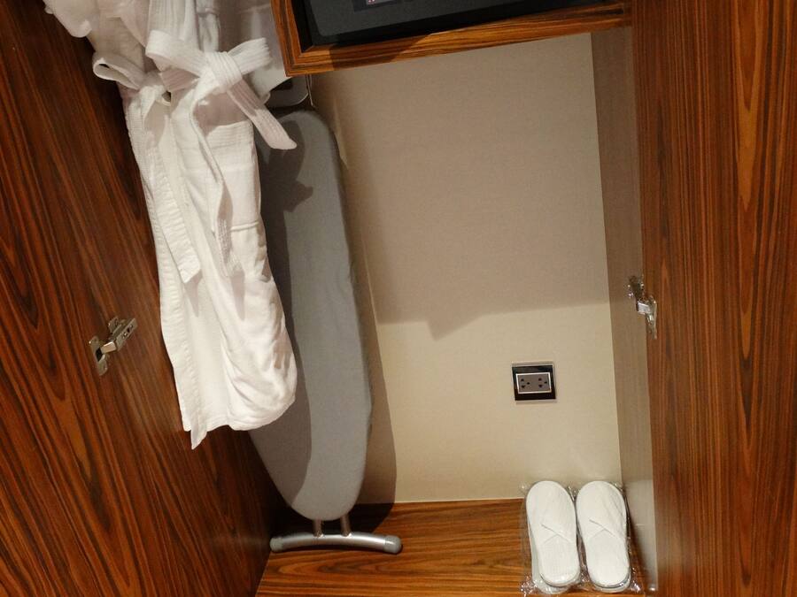 A wooden closet with a built-in shoe rack and a small shelf with a remote control.