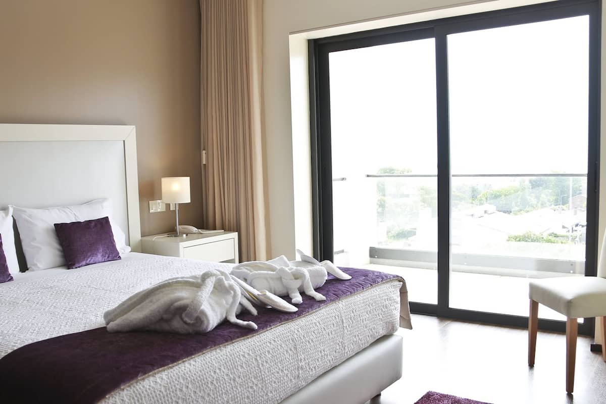 Une chambre d’hôtel avec un grand lit, une table de chevet avec une lampe et une vue sur l’extérieur grâce à une porte coulissante.