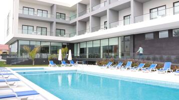 En säsongsöppen utomhuspool, parasoller och solstolar