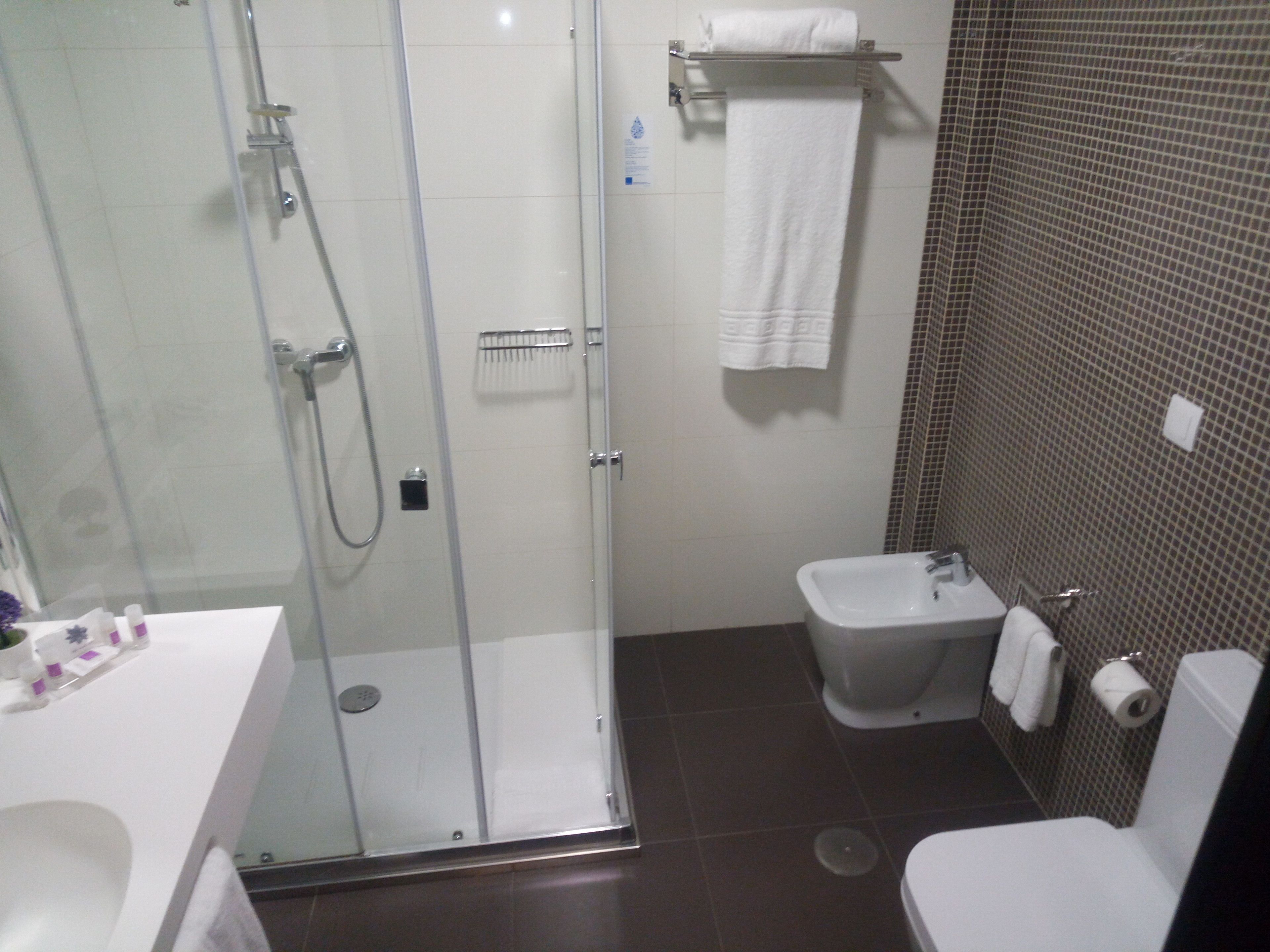 Un baño con cabina de ducha de vidrio, un lavamanos blanco, un bidé y un inodoro.