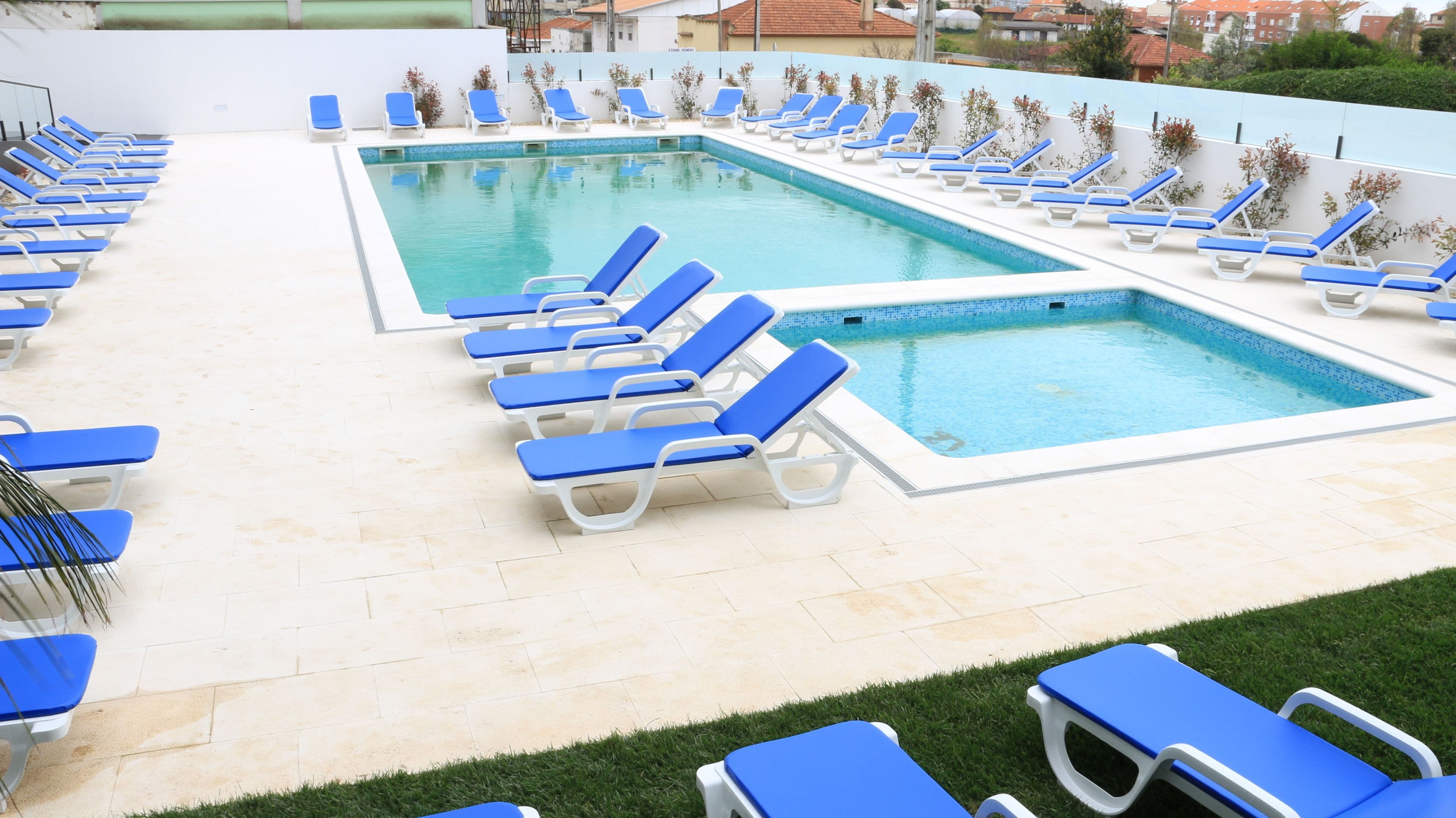 A swimming pool with multiple blue lounge chairs arranged around it.