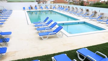 A swimming pool with multiple blue lounge chairs arranged around it.