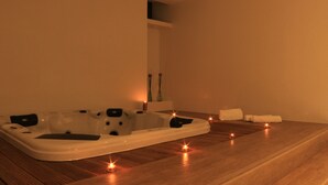 A spa room with a large bathtub, candles, and towels on the floor. - Monte Lírio Hotel (Espinho)