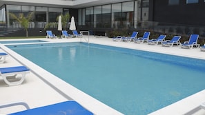 A swimming pool with blue lounge chairs and white umbrellas.