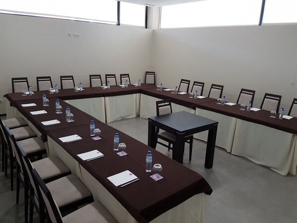 A conference room with long tables, chairs, and water bottles.