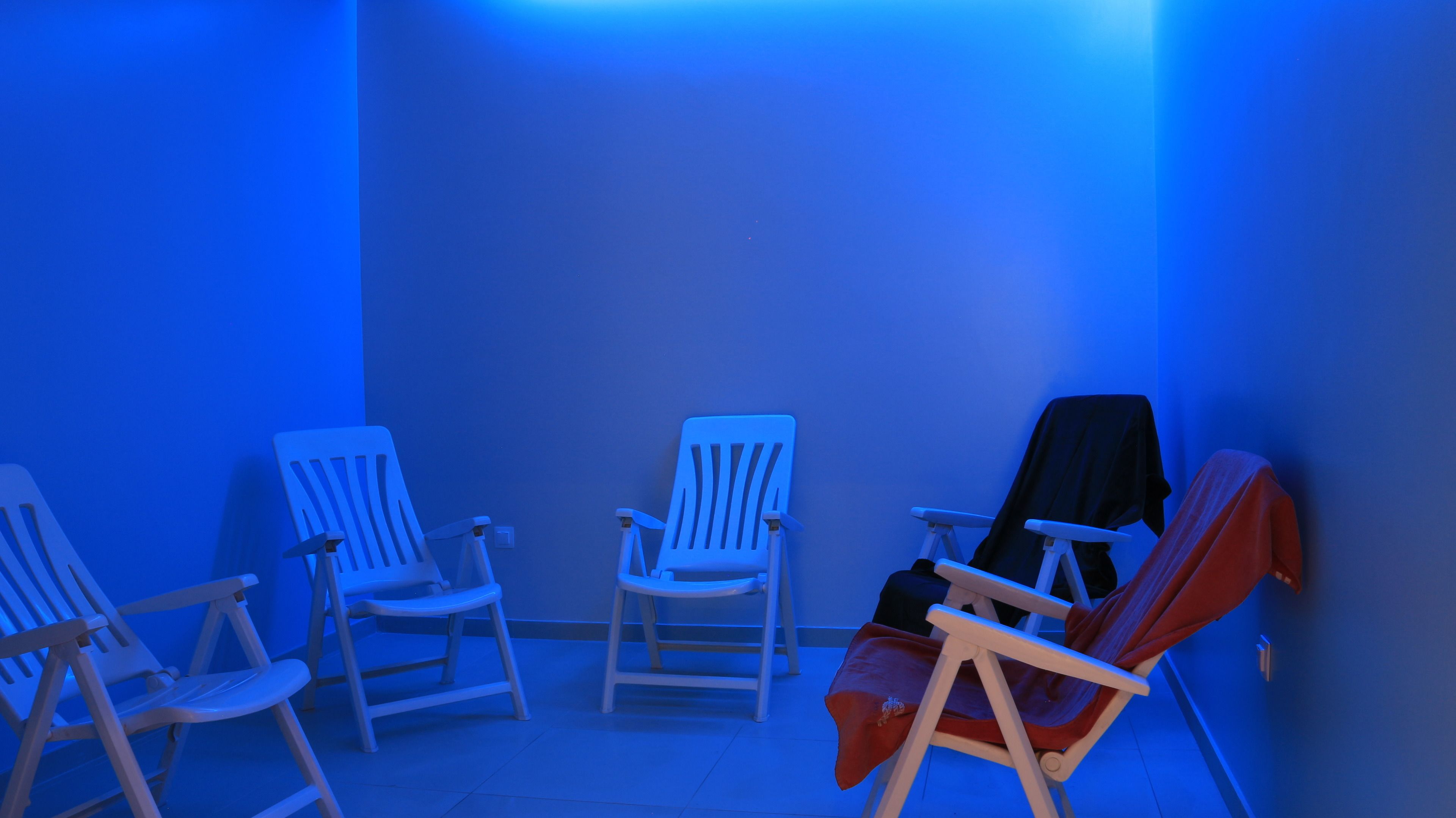A room with four chairs, one of which is covered with a black cloth.