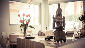 A reception desk with a Buddha statue, a vase of flowers, and a laptop. - Hotel Ristorante Rinelli (Margherita di Savoia)