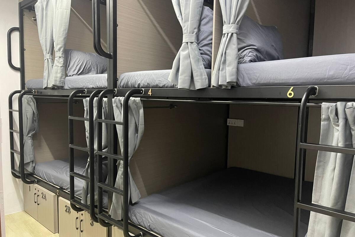 A bunk bed room with two beds, each with a pull-up ladder, and a small storage cabinet below.