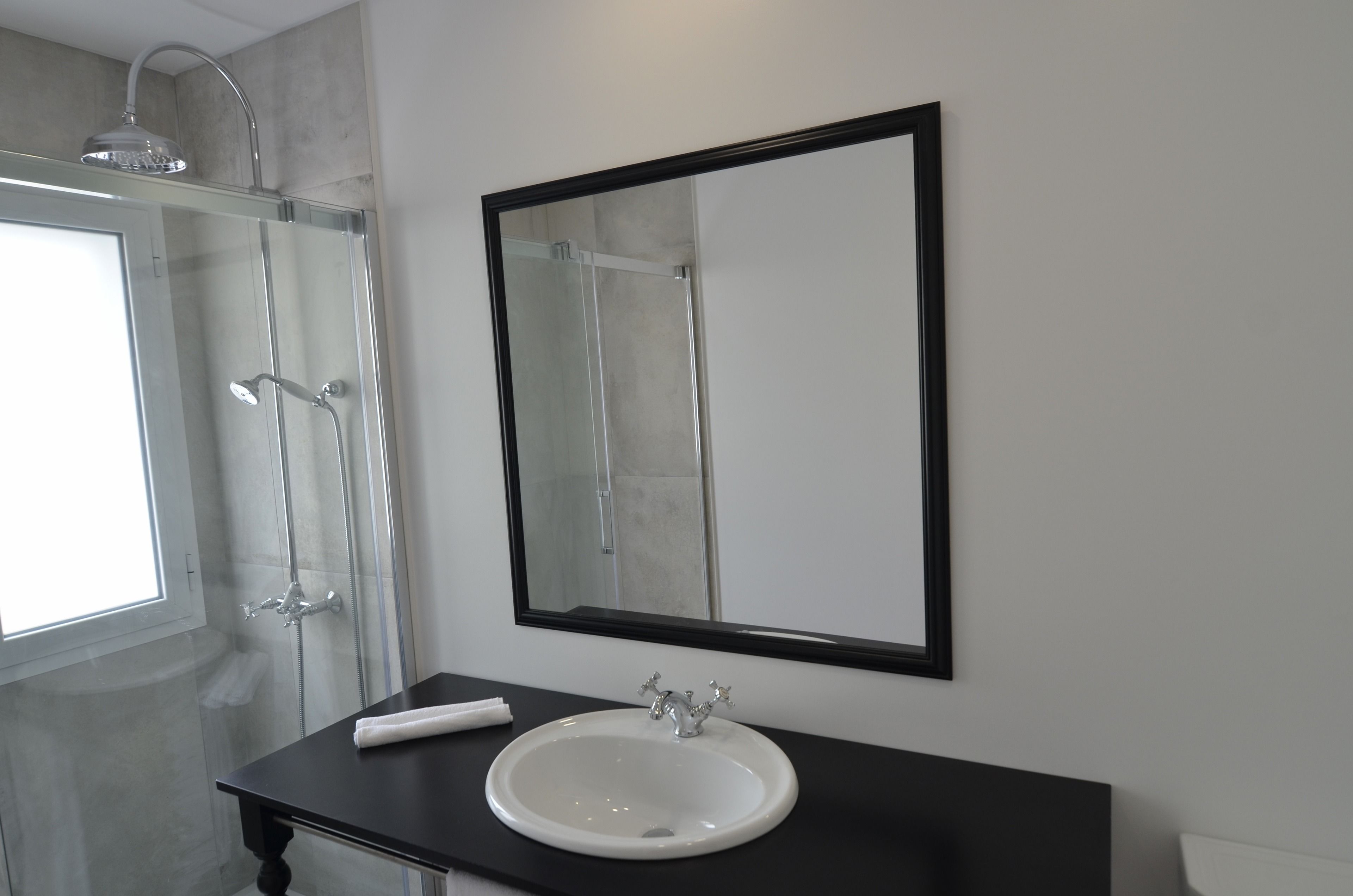 A bathroom with a white sink, a large mirror, and a glass-enclosed shower.