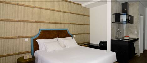 Ein Hotelzimmer mit Bett, Nachttisch und einem kleinen Badezimmer mit Waschbecken und Spiegel.