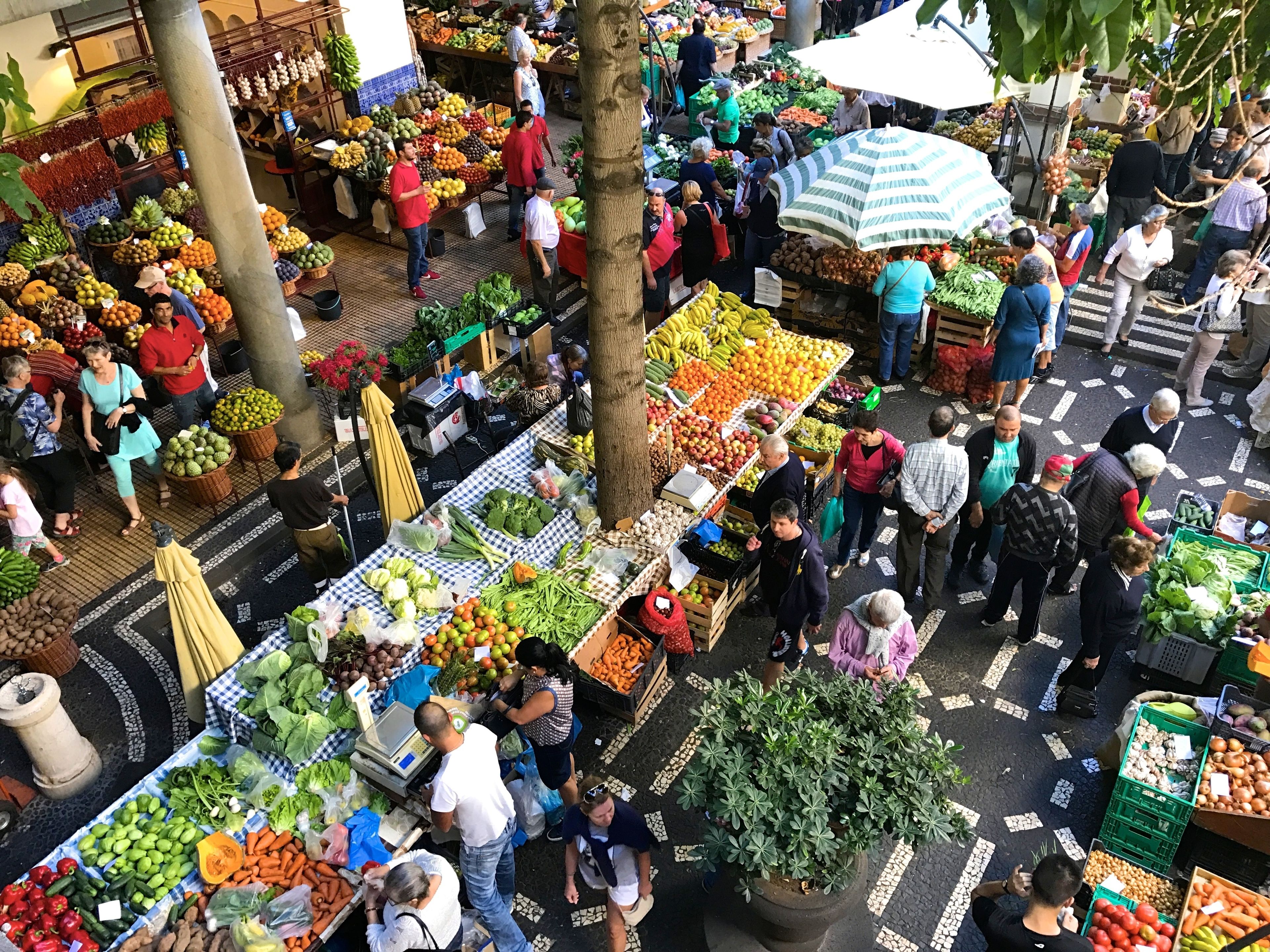 A bustling outdoor market with various stalls selling fresh produce and fruits.