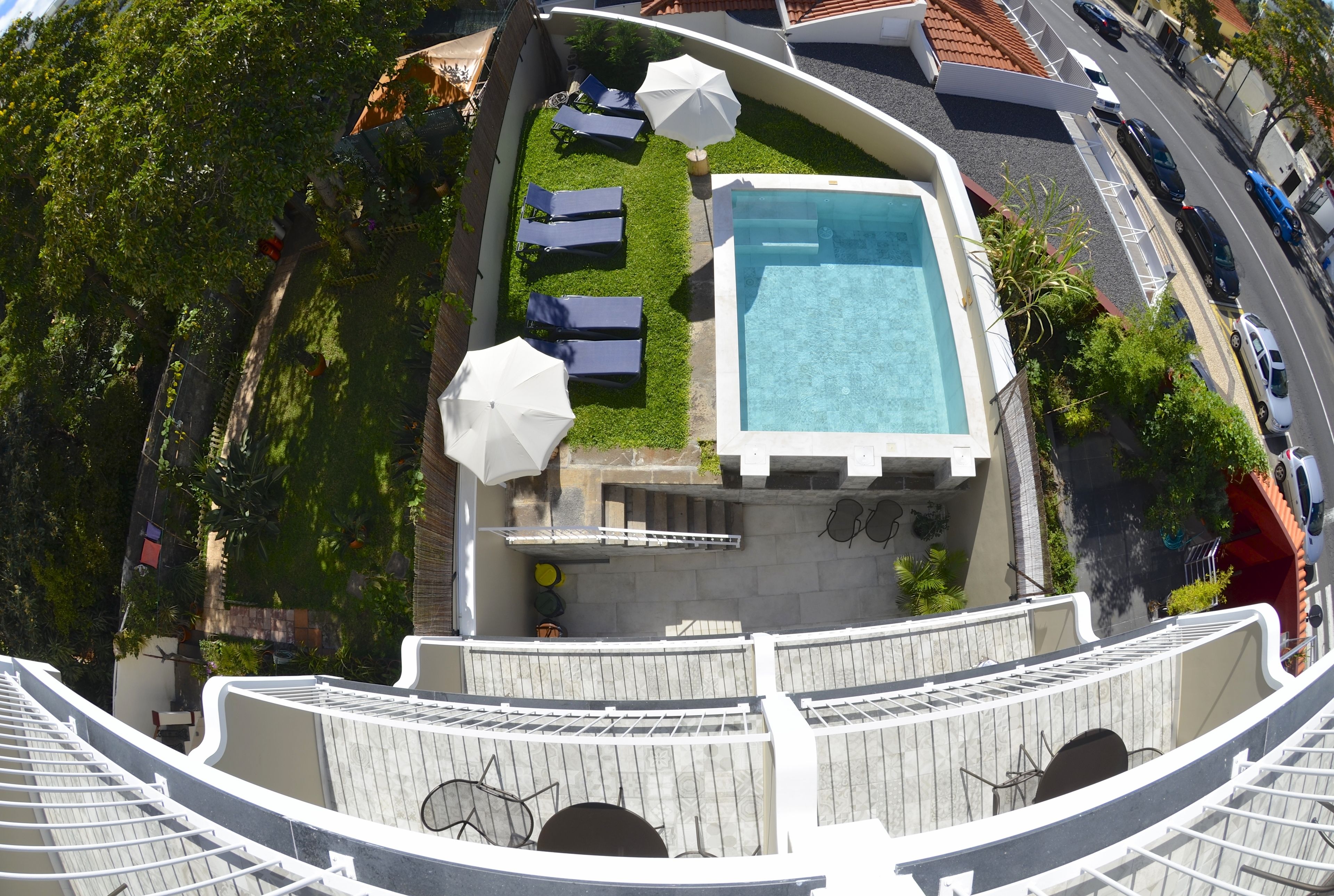 Ein Poolbereich auf dem Dach mit Liegestühlen und Sonnenschirmen, umgeben von einer gebogenen weißen Struktur.