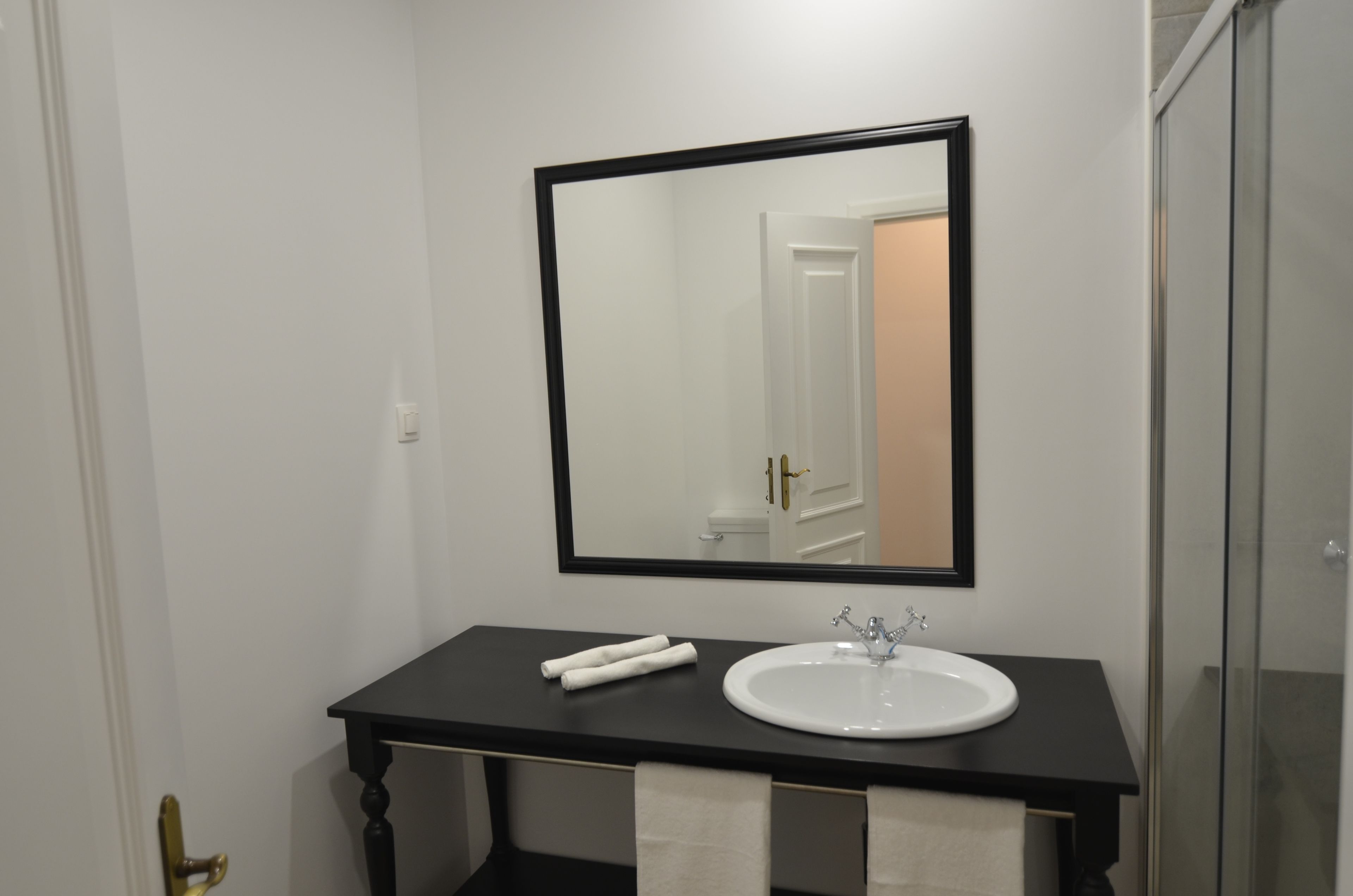 A bathroom with a black countertop, a white sink, and a large mirror.