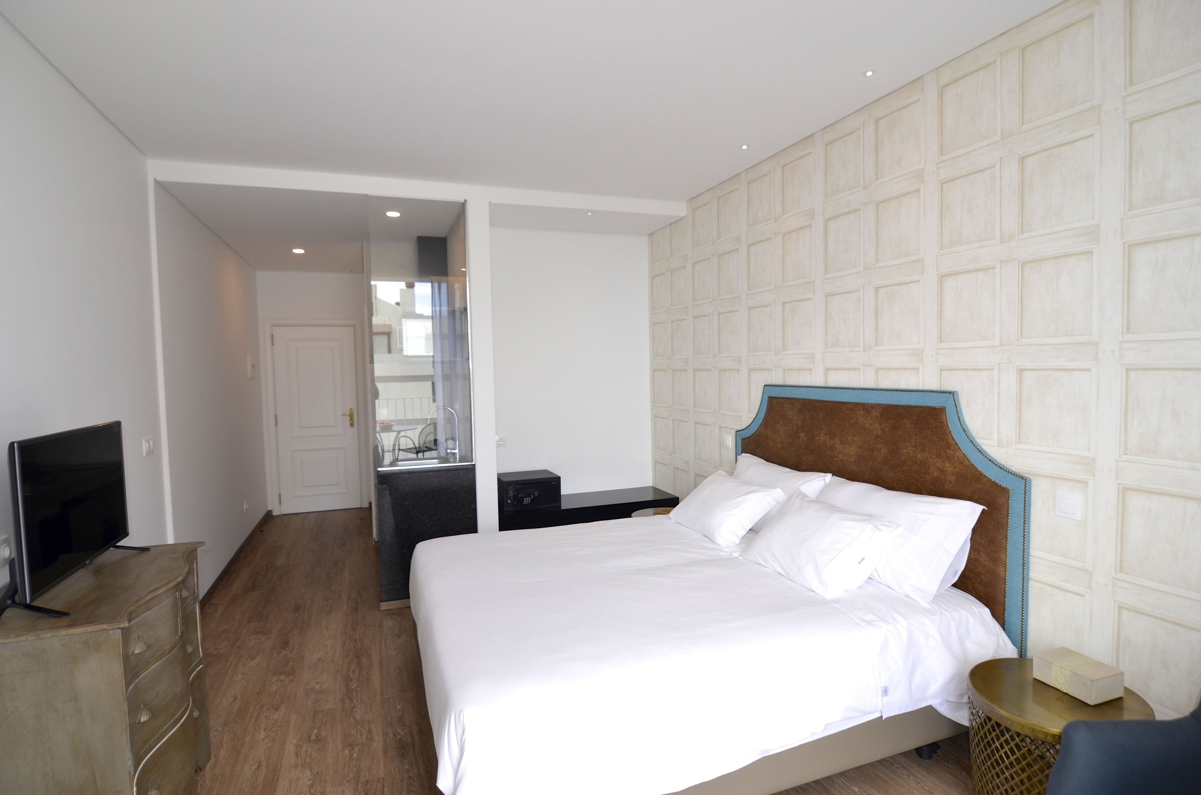 A hotel room with a large bed, a television on a dresser, and a bathroom visible through an open door.